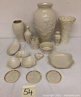 Full view of all ivory Lenox ceramic items including vases, serving dishes, coasters, and trinkets arranged on a table.
