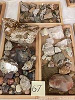 View of multiple mineral and rock specimens on several wooden trays showing different sizes and colors of rocks and minerals.