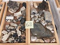 Two wooden trays containing a mix of mineral rock samples of various sizes and colors, showing rough textures and crystalline structures.