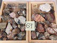 Image showing two wooden trays filled with various mineral rocks and smaller mineral samples in plastic cases. A numbered paper '69' is placed between trays.