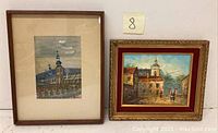 Two framed oil paintings showing religious building and courtyard scenes, side by side against a white wall.