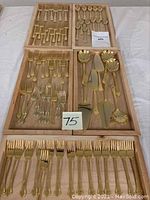 Full set of gold wash flatware organized in wooden trays for display