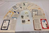Wide view showing multiple first day issue stamp envelopes laid out on table. Various historical commemorative covers.
