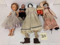 Group photo of six dolls showing full bodies and outfits lying flat