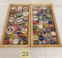 Full lot consisting of two wooden trays filled with various vintage political campaign pins arranged for display and photography.