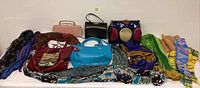 Overview of all handbags, gloves and multi-colored scarves arranged on table.