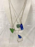 Front view of all four necklaces on display bust showing colors and wire wrapping of sea glass pendants.