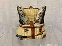 Front view of the woven fishing basket holding two fish-shaped salt and pepper shakers, showing detailed textured ceramic work and fishing gear accents.