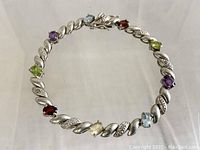 Full top view of bracelet showing twisted silver links alternating smooth and textured finishes with various oval colored stones.