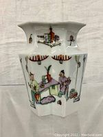 Front view of antique porcelain vase showing hand-painted scene of two men in traditional dress near a table with various objects.