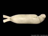 Front view of off-white sea lion carving on black background