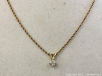 Close up of the solitaire pendant showing the single round cut stone and the pendant bail attached to the 10K gold chain.