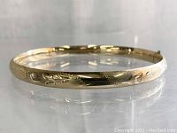Side profile of slim bangle showing engraved floral and scroll exterior