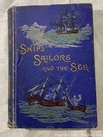 Front cover of the antique book 'Ships Sailors and the Sea' showing detailed artwork of ships and sea birds, title embossed in gold.