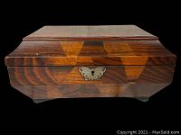 Front view of antique wooden box with butterfly-shaped keyhole escutcheon and geometric wood inlay pattern.