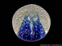 Top view of the clear glass paperweight with visible blue and white swirling pattern inside and scattered bubbles.