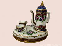 Front angle close-up showing detailed hand painting and gold accents on teapot and teacups pill box.
