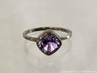 Front view of ring showing square-cut purple stone set in sterling silver band.