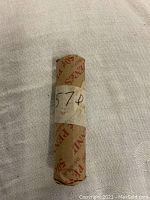 Photo of the cylindrical roll wrapped in original brown paper labeled '50¢' containing 1957D Lincoln Wheat pennies.