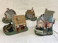 Photo showing five vintage miniature houses arranged on cloth background.
