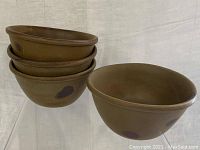 Four large brown stoneware bowls with tavernware glaze featuring dark spots and thick rims, stacked three with one next to stack.