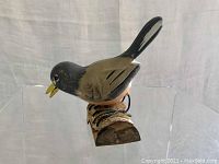 Side view of small vintage robin bird decoy mounted on wood showing hand painted details and paint wear.