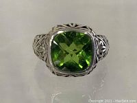 Top view showing bright green square cushion-cut stone set in sterling silver ring with detailed filigree band.