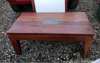 Front view of the rectangular mid century modern coffee table showing wood grain, ceramic tile, and leg support.