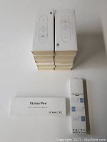 Stack of 10 boxed Doosl wireless presenter remotes model DSIT021 and 2 boxed stylus pens arranged on a white surface