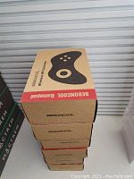 Stack of six beige and red cardboard boxes, each showing Beboncool wireless controller branding and controller silhouette.