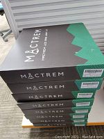 Stack of eight black and green MACTREM branded boxes, each containing a ring light kit.