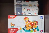 Boxes for BeebeeRun Construction Vehicles and HUANGER Musical Piano placed on shelf