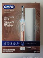Front view of the unopened box showing Oral-B Genius 6000 electric toothbrush, rose gold colored, with key features and Bluetooth logo.
