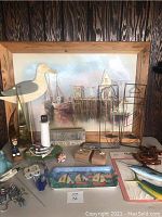 Full view of the framed harbor boat artwork and assorted beach-themed collectibles on table