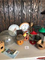 Photo of assorted bird feeders, decorative birdhouses and two wall clocks on a table against dark wood paneling.