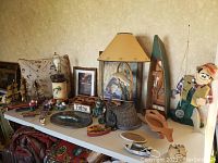 Wide view of various fishing decorative items arranged on a table including figurines, plaques, art, a lamp, and wooden fishing rod holders.
