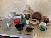 Full view of antique oil lamp, Longaberger basket, various glass Pyrex containers with lids, small toaster oven, cookware and kitchen appliances on a table