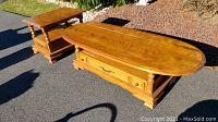 Photo showing both the Riverside Birchwood coffee table and end table in sunlight on asphalt, highlighting the wood grain and finish.