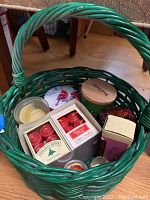 Green wicker basket showing various boxes of red votive candles and candle jars inside