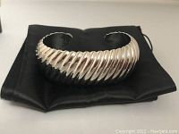 Silver-tone ribbed cuff bracelet on black satin pouch