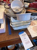 Stack of glass bakeware including clear rectangular Corning Ware dishes and round bowls, with a white ceramic souffle dish on top
