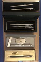 Two sets of chrome Cross pen and pencil sets in their original cases, a Zippo pen set with penknife/file money clip in box, and a black Cross pencil.