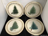 Five Lenox collectible Christmas plates displayed on black fabric surface. Each plate displays a different pine tree design with gold decorative border. Four plates dated 1977 through 1980.