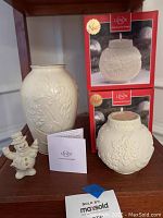 Photo shows Lenox Masterpiece vase, two Ornamental Glow votives in boxes, and small snowman figurine on a shelf with Lenox leaflet.