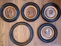 Four framed solid copper collector plates depicting Norman Rockwell self-portrait, Peace Corp, Lindbergh and Abraham Lincoln, plus one empty frame on wood floor.