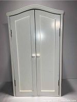White wooden doll wardrobe with closed double doors
