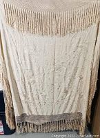 Full view of crocheted bedspread hanging with fringe showing