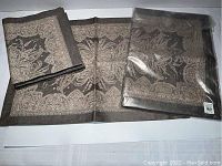 Four rectangular Williams Sonoma Siena Grey placemats, one folded and still in original packaging, two laid flat showing design