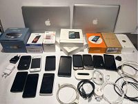 Overview of two MacBook laptops in back, boxed devices, unboxed phones and cables on table