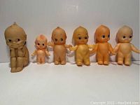 Photo showing six vintage Kewpie dolls with different sizes and colors aligned in a row